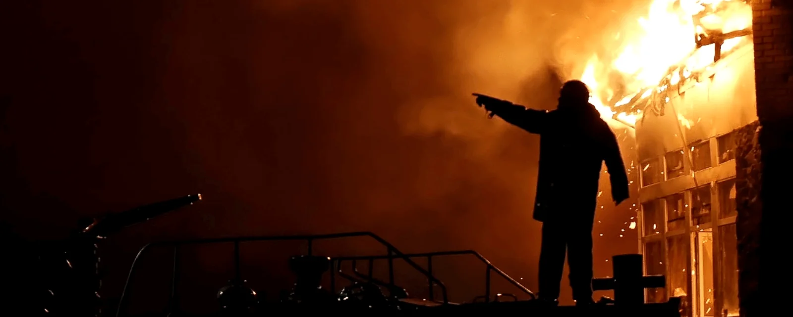 Firefighter silhouetted by a burning building